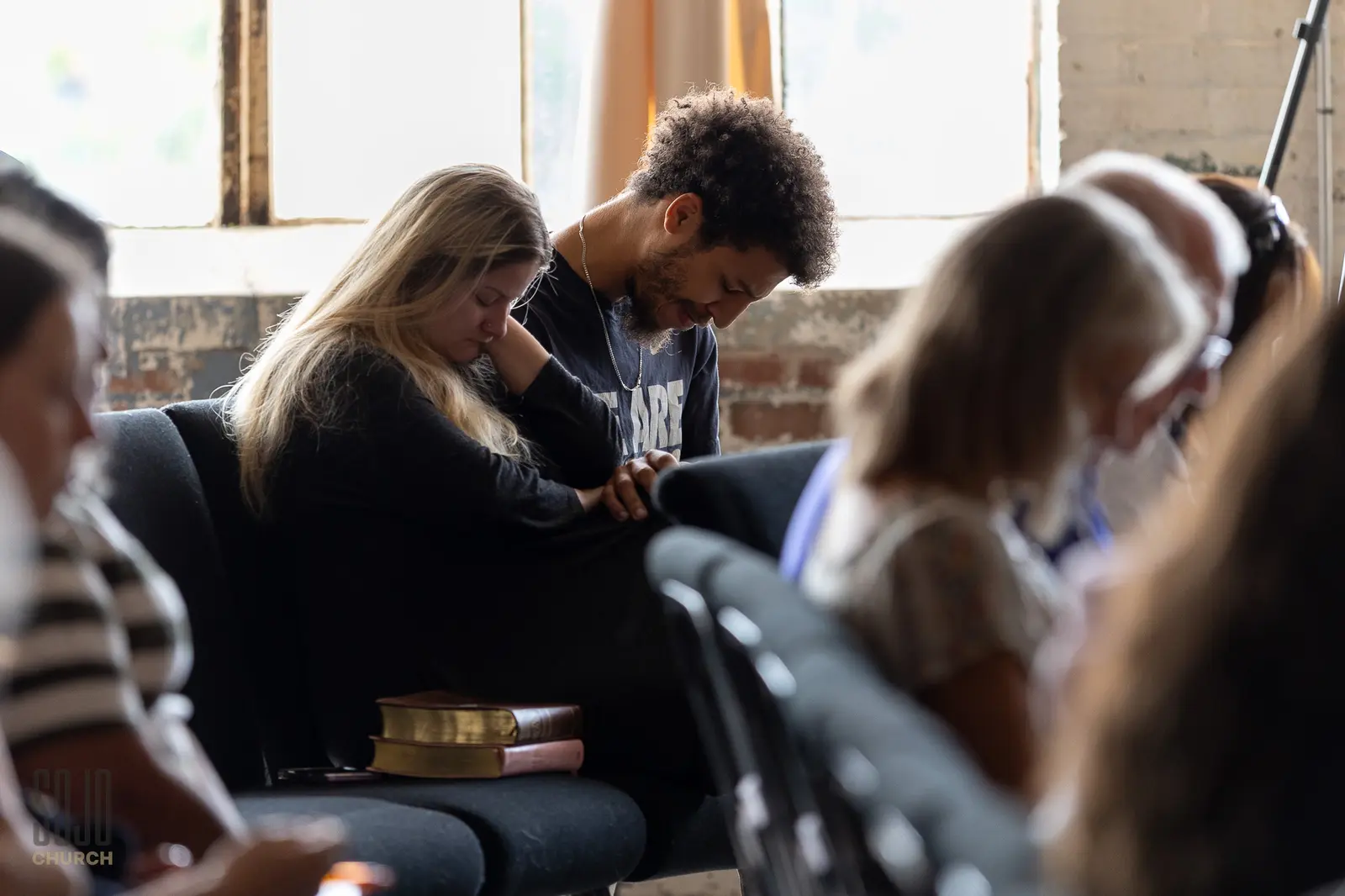 A couple praying with their Bibles beside them during the service