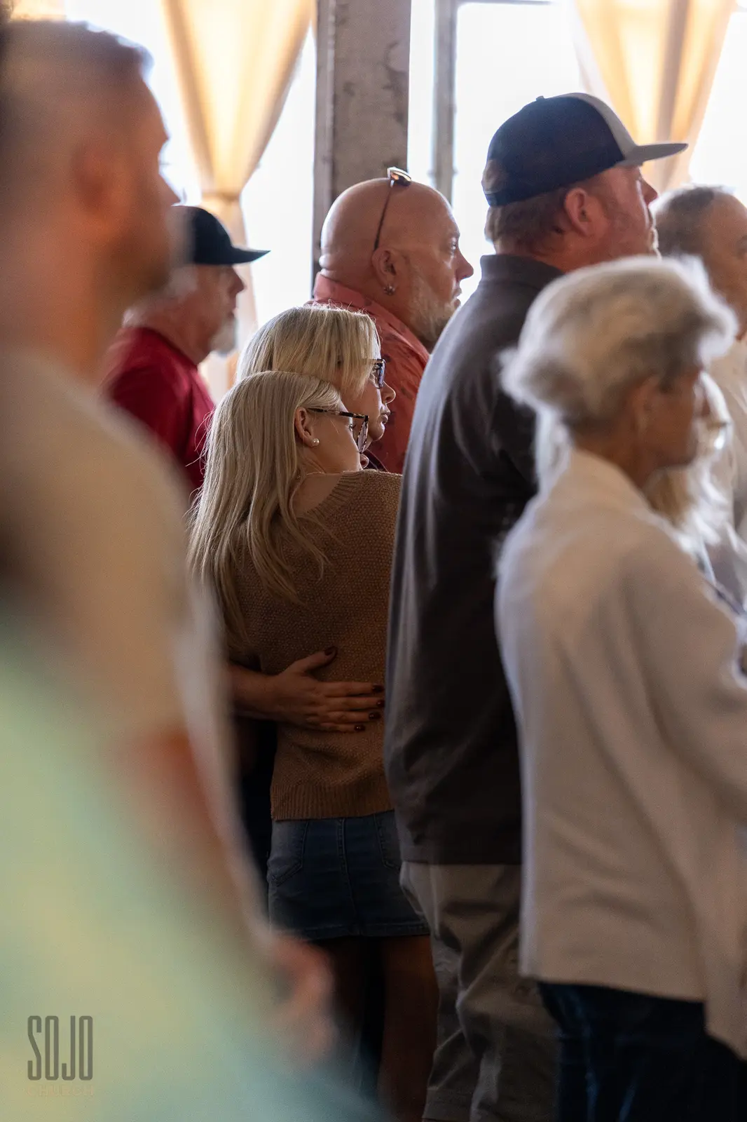 Two people embracing in the congregation during worship at the Kettle Room