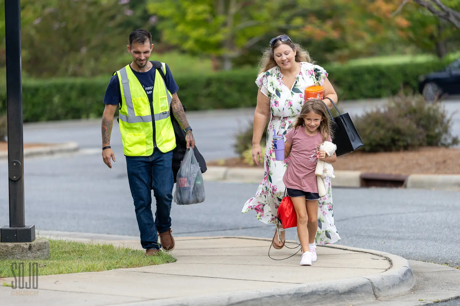 A family walking in with a SOJO greeter on Sunday morning