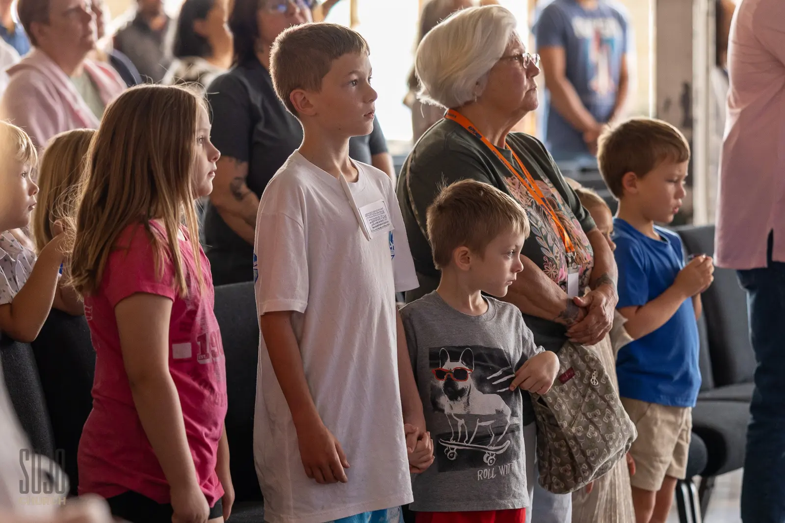 Three generations of one family standing together in worship at the Kettle Room