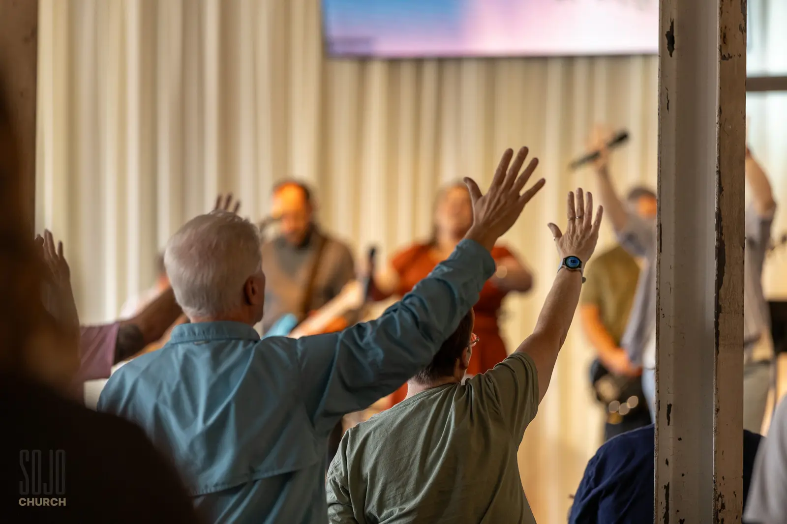 Hands lifted toward the stage in worship at the Kettle Room