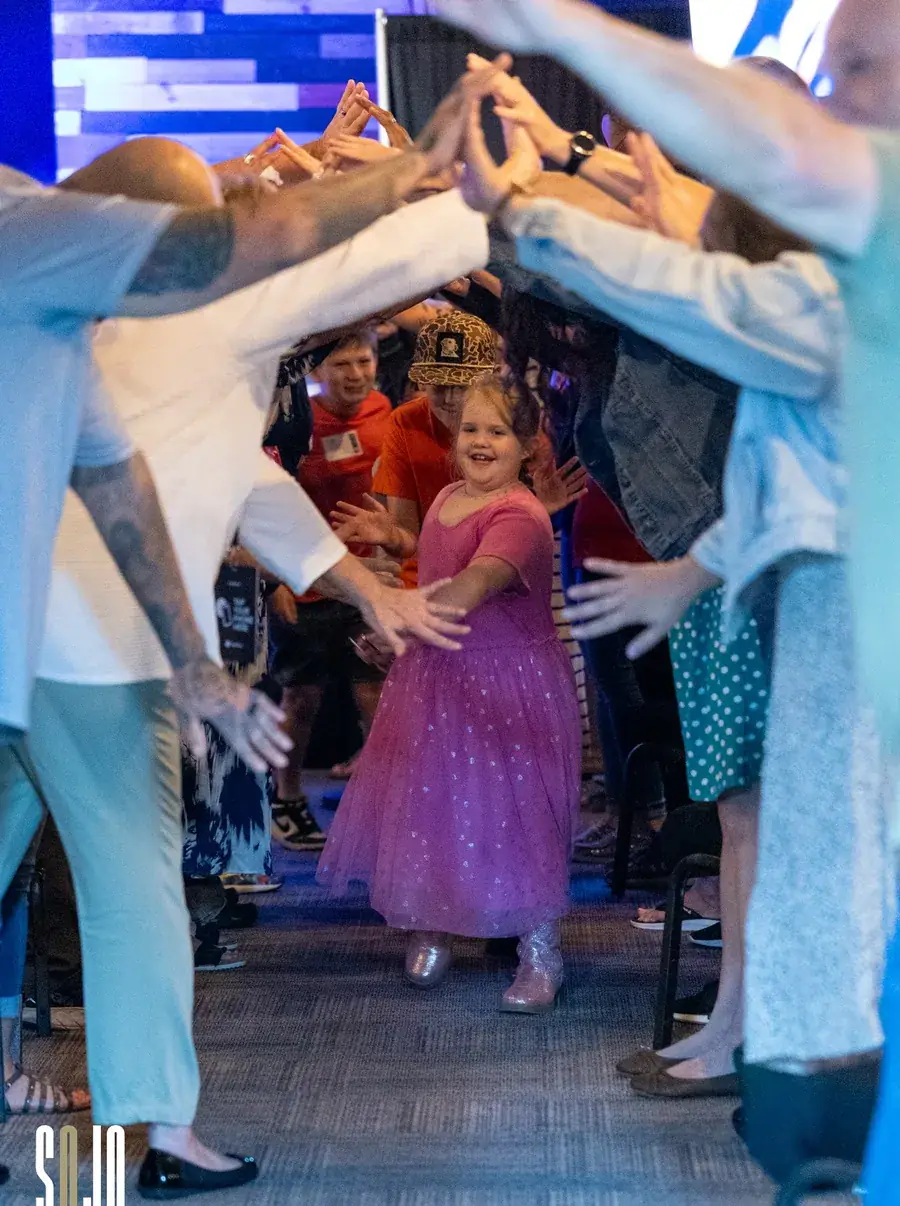 A child running through a tunnel of cheering SOJO volunteers