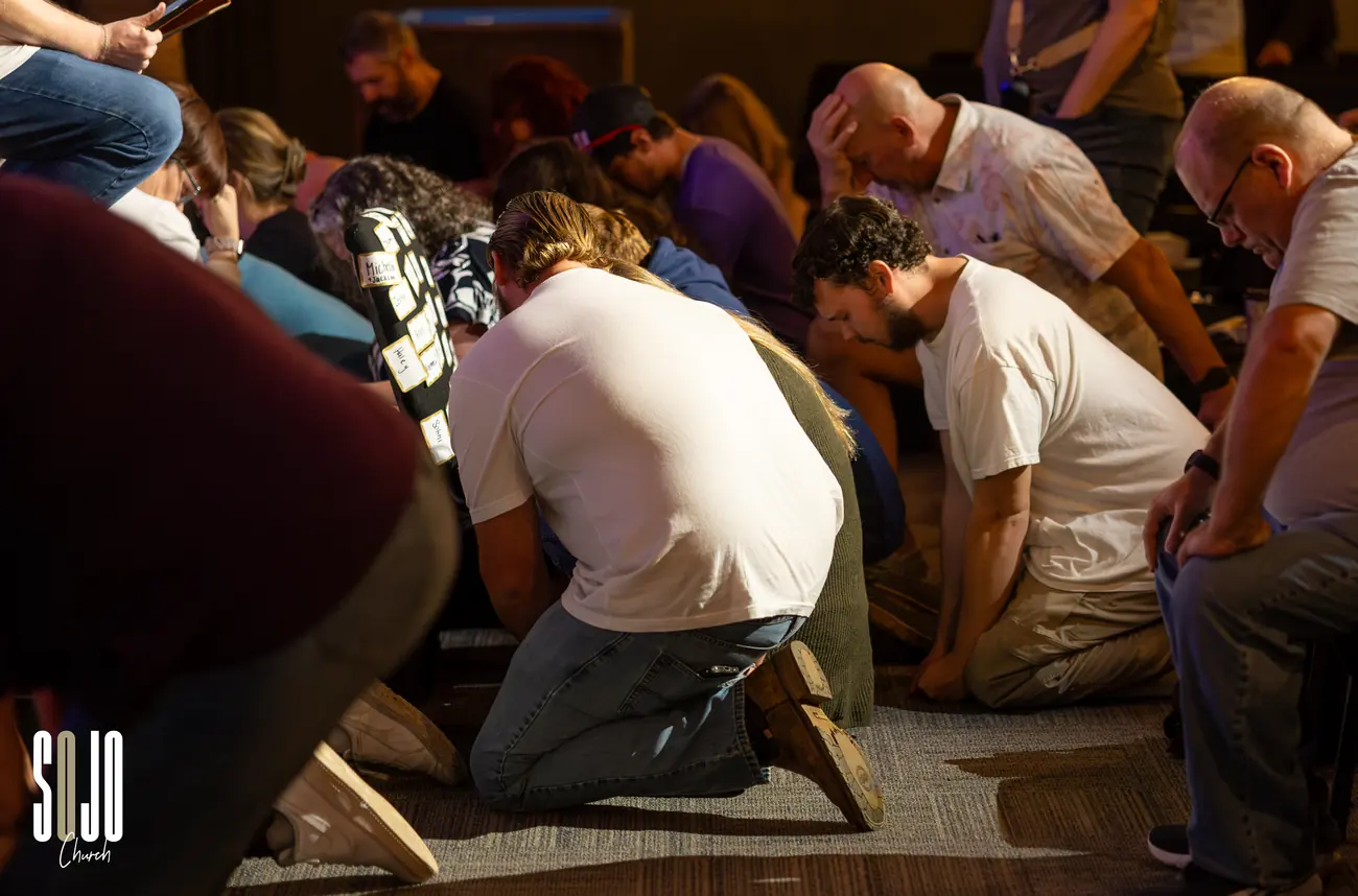 The SOJO family kneeling and praying over one another