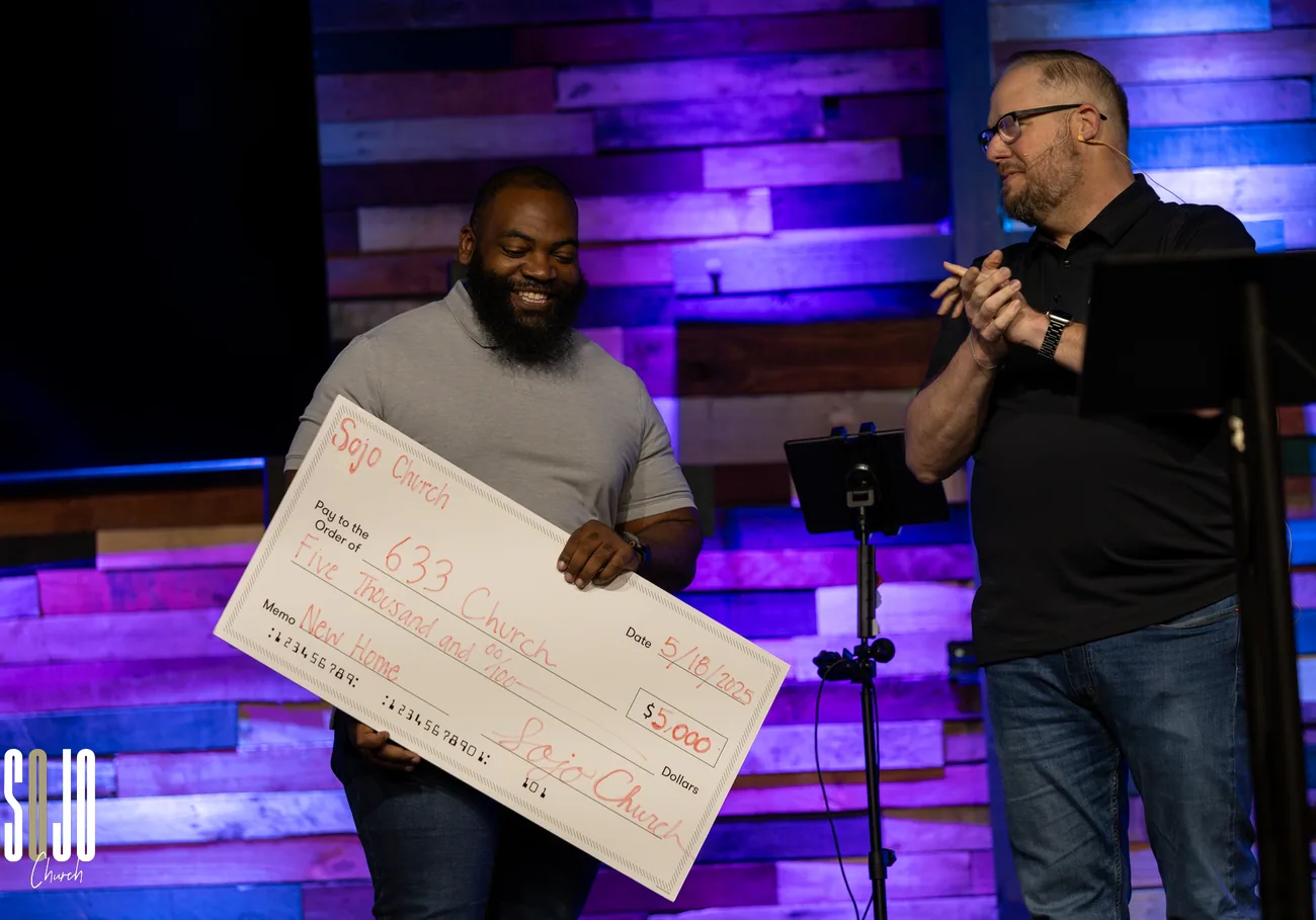 A SOJO ministry partner receiving a giving check on stage