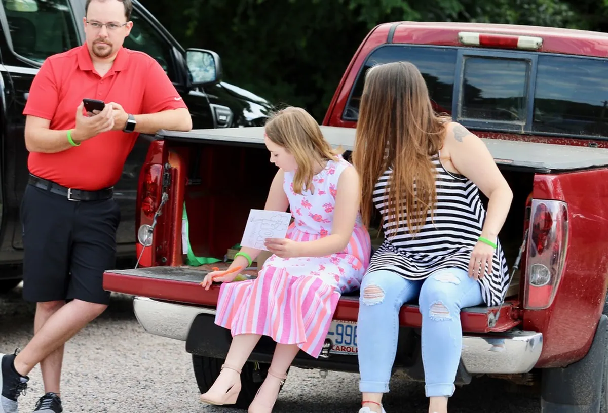 A family sitting on a tailgate during drive-in church