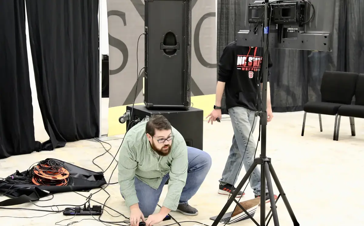 A volunteer running cables to set up for Sunday