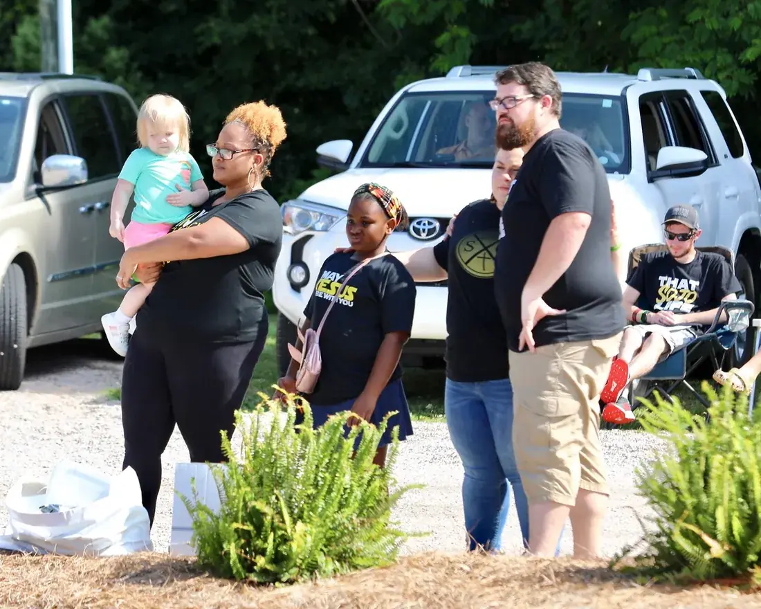 Families gathered in the gravel lot for drive-in church