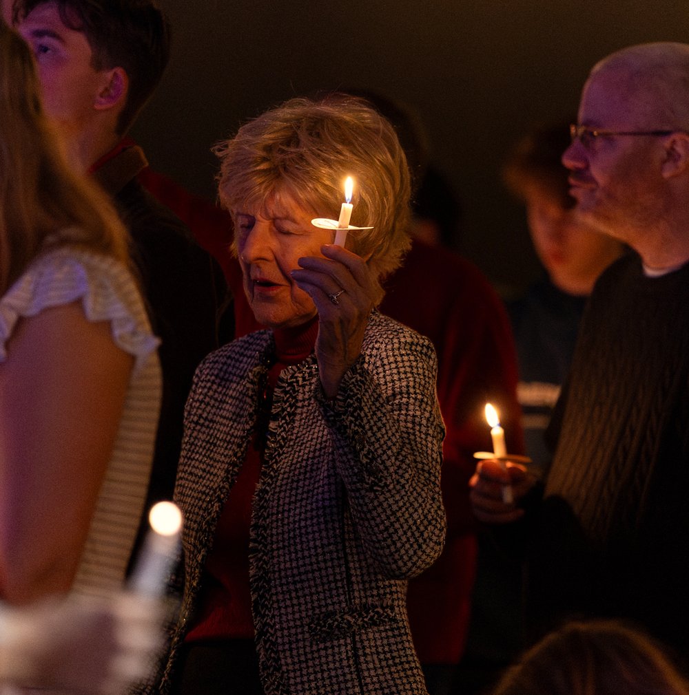 A woman holding a lit candle on Christmas Eve at SOJO
