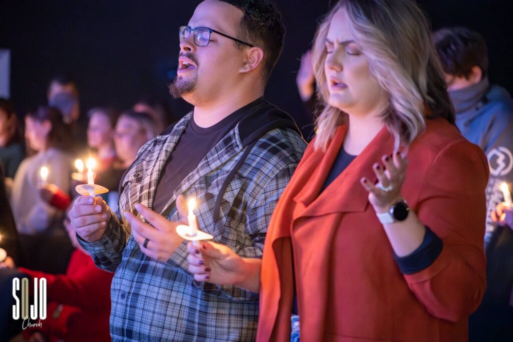 Two people holding candles in a church service.